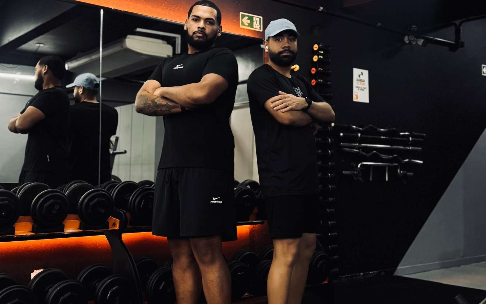 Sala de musculação da Be Fitness, com o rack de halteres iluminado em laranja